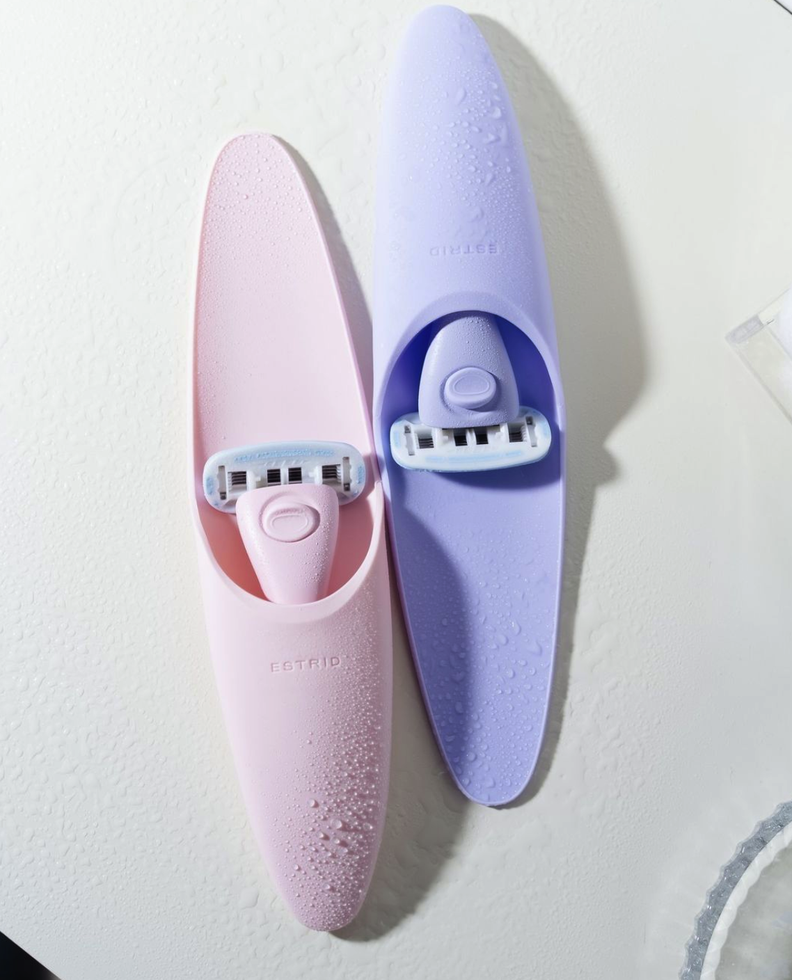 Two razors in their holsters next to each other - one pastel pink and one pastel purple.